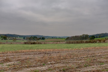 Fototapeta na wymiar Plowed pasture in the Ardennes with a village in the background