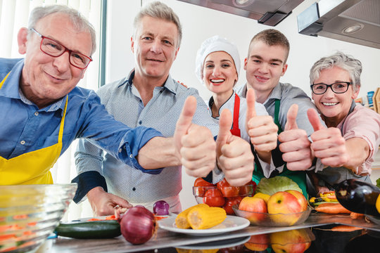Trainees and their nutritionist in a training kitchen showing thumbs