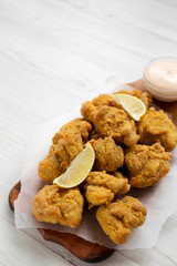 Homemade traditional japanese fried chicken Karaage on a rustic wooden board over white wooden surface, low angle view. Copy space.