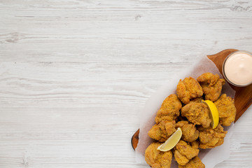 Top view, homemade traditional japanese fried chicken Karaage on a rustic wooden board on a white wooden surface. Flat lay, overhead, from above. Copy space.