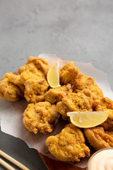 Homemade traditional japanese fried chicken Karaage on a rustic wooden board over gray background, side view. Copy space.
