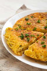 Homemade spaghetti omelette on a white plate, low angle view. Close-up.