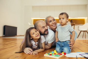 Fototapeta premium Cheerful family happy together on floor. Portrait of caucasian family lying, smiling. Happy family concept