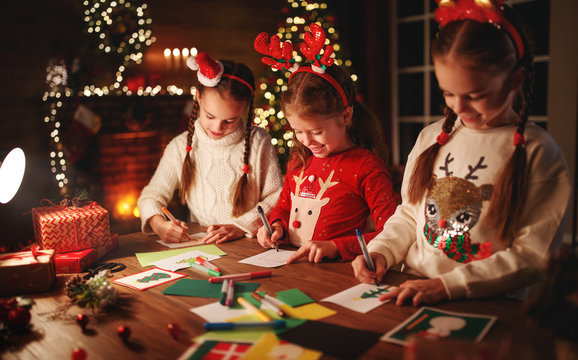 happy friends kids draw decorations and write  letter to Santa near Christmas tree.