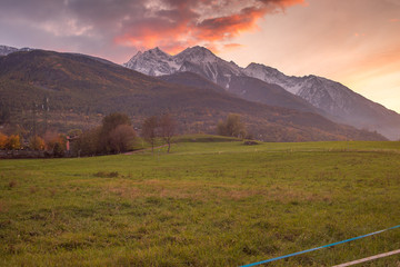 Countryside landscape with mountains in the background at sunset. Yellow and red sky with clouds