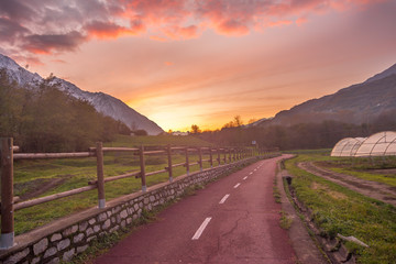 Countryside landscape with mountains in the background at sunset. Yellow and red sky with clouds