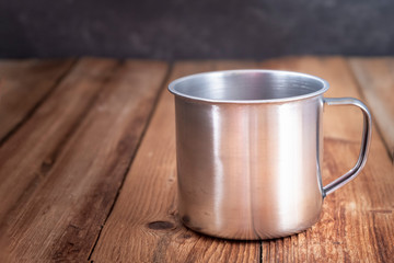 Empty aluminum mug on brown wooden background.