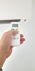 Modern airconditioner unit with a hand holding a remote.