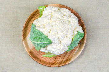Top view of cauliflower on wooden dish on cloth surface