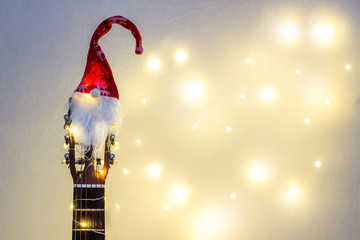 Acoustic Guitar with red Santa hat and light garland. Christmas music song concept with copyspace