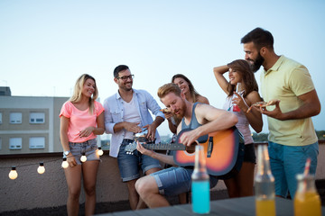 Obraz premium Group of happy friends having party on rooftop
