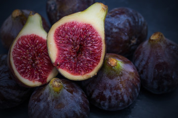 natural black figs grouped and open on black background