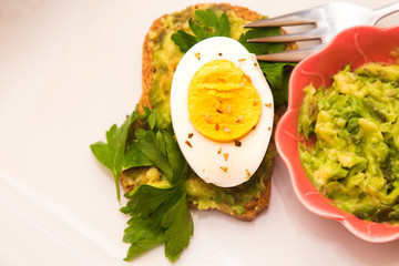 Guacamole toast and hard boiled egg with parsley