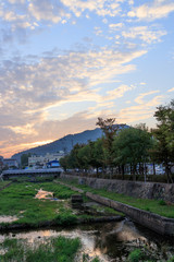 Naju-si, Jeollanam-do / South Korea - OCTOBER 17, 2019: Mountain sky sunset clouds river reflection portrait