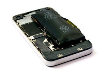 Swollen lithium ion polymer battery inside a mobile phone on white background isolated