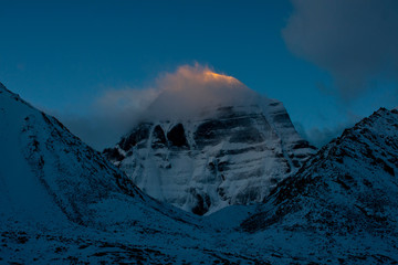Kailash north face sunrise Tibet cloud shrouded summit blue sky background after snowfall