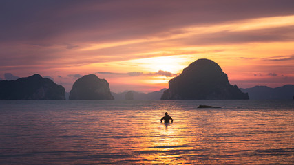 A man standing on beach confront to beautiful sunset and dramatic sky in Krabi Thailand