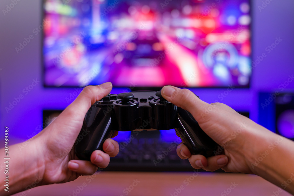 Poster joypad in hands. gaming concept. computer display with racing game and rgb light in background.