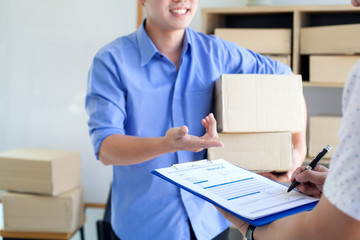 Shopping Online concept, Shipping shopping online,Young start up small business owner writing address on cardboard box with computer
