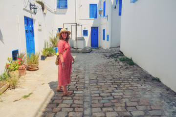 Obraz na płótnie Canvas Girl stands in the courtyard with blue windows and doors with Arabic ornaments. Texture of Islamic symbols in Sidi Bou said, Tunisia, Africa