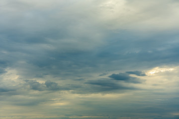 Overcast sky with thick gray and white clouds and a setting sun