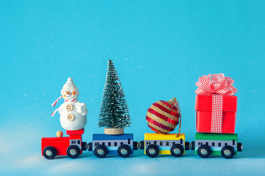 Christmas tree and gift box, ball and snowman on toy train on blue background. Gifts and congratulations concept.