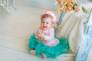 Fototapeta premium Image of sweet baby girl in a wreath, closeup portrait of cute 8 month-old smiling girl, toddler.