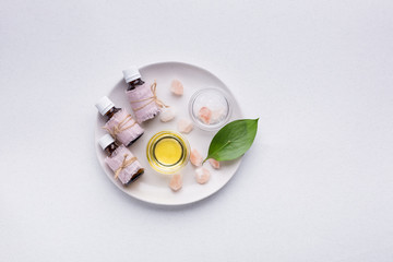 Bottles with aromatic oils and a branch of white eustoma on a white background