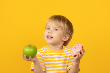 Happy child holding donut and apple