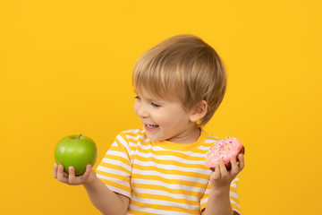 Happy child holding donut and apple