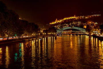 Fototapeta premium Pedestrian Bridge of Peace over the Kura River, Narikala Fortress and Kartlis Deda Monument in Tbilisi, Georgia