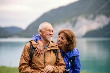 Foto op Plexiglas Senior pensioner couple hiking by lake in nature, resting. © Halfpoint