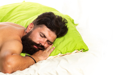 Handsome man in bed. Bearded man sleeping on bed in bedroom. Good morning. Young man sleeping in bed with pillows at home.