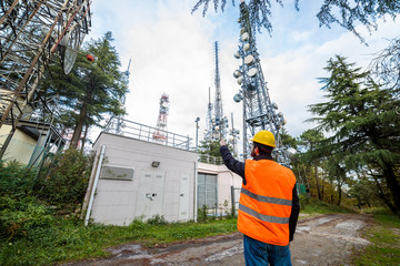 Ingegnere delle telecomunicazioni con nuova antenna telefonica 5G in montagna per internet.