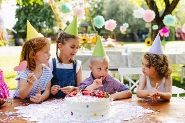 Down syndrome child with friends on birthday party outdoors in garden.