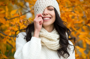 Beautiful woman walking outdoors in autumn. Smiling girl collects yellow leaves in autumn. Young woman enjoying autumn weather.