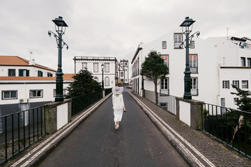 Woman traveling in Azores island walking in city with white buildings