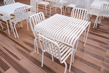 White tables and chairs without people in a street summer cafe