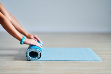 Young woman rolling yoga mat at home