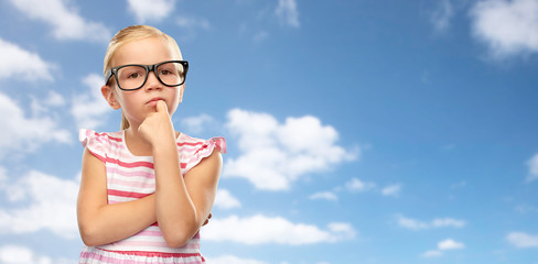 education, school and vision concept - cute little girl in black glasses over blue sky and clouds background