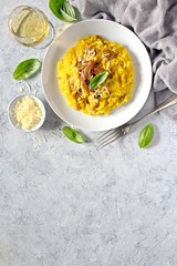 Traditional Italian risotto with mushrooms, saffron and parmesan cheese on white wooden background. Top view with copy space.