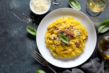 Traditional Italian risotto with mushrooms, saffron and parmesan cheese on white wooden background. Top view with copy space.