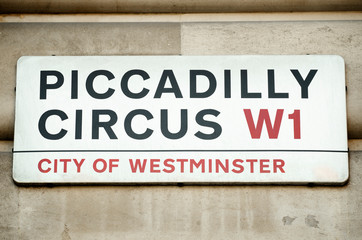 Naklejka premium Piccadilly Circus street sign hangs from traditionally English stone building in the City of Westminster, London, UK
