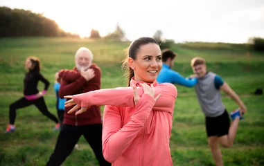 Fotobehang Large group of fit and active people stretching after doing exercise in nature. © Halfpoint