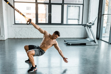 handsome sportsman working out on suspension trainer in sports center