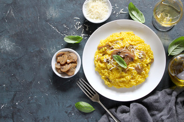 Traditional Italian risotto with mushrooms, saffron and parmesan cheese on white wooden background. Top view with copy space.