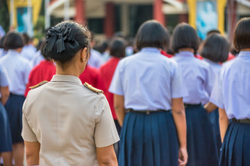 The high school teachers in Thai government teacher uniform are standing among students, Thailand, southeast Asia.