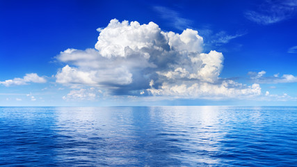 White cumulus clouds in blue sky over sea landscape, big cloud above ocean water panorama, horizon,...