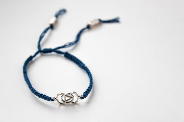 blue braded bracelet with chakra (ajna) on the left in the photoon white background