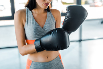 cropped view of sportswoman in boxing gloves in sports center